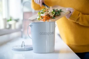 A woman scraps food scraps into a kitchen compost bucket