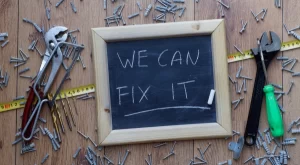 A chalkboard reads "We CAN FIX IT" surrounded by tools